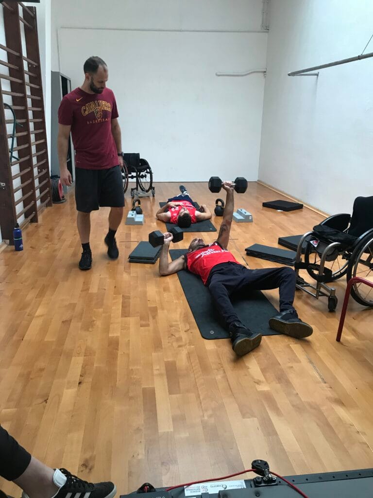 Photo d'un athlète paralympique couché au sol, soulevant des poids dans chaque main