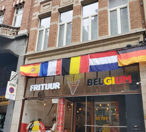 Une façade d'un immeuble avec des drapeaux de différents pays accrochés au-dessus de l'entrée